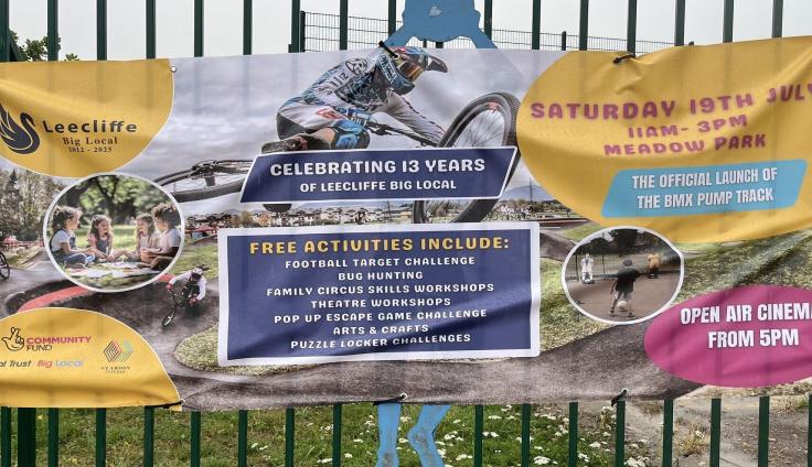 A large plastic banner tied to railings reading 'Celebrating 13 years' with photos and text.