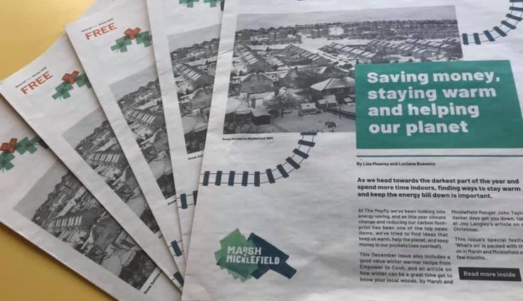 Five copies of a newspaper are laid out in a fan pattern on a yellow table. The top left-hand corner says "FREE" in. red letters. The top copy in a green box shows a front page with the headline "Saving money, staying warm and helping the planet". A black and white photo of houses is behind it. The Marsh & Micklefield logo is in the bottom left of the page.