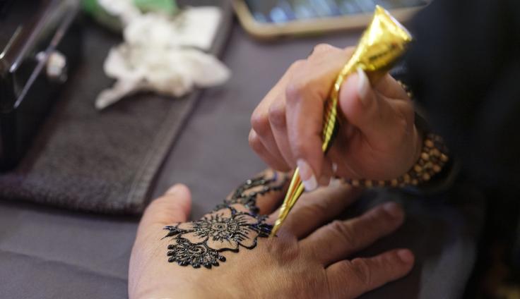 A person applies henna ink to a hand.