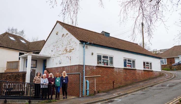 A group of people next to a building built into the side of a steep hill.