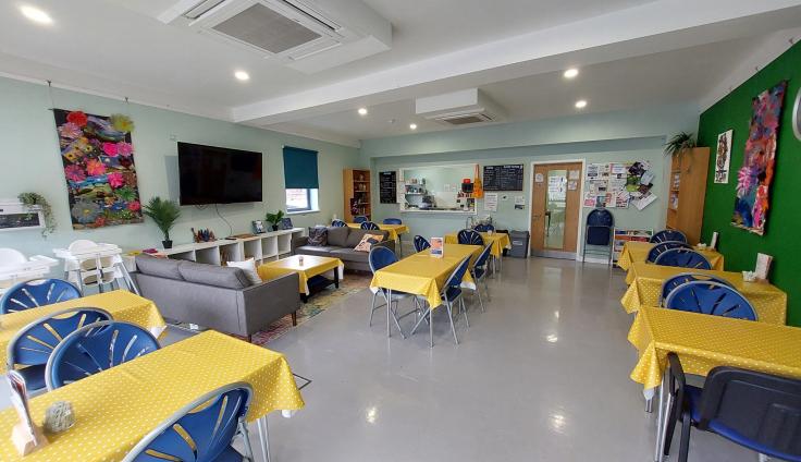 A large open space with tables and chairs set out in cafe style.