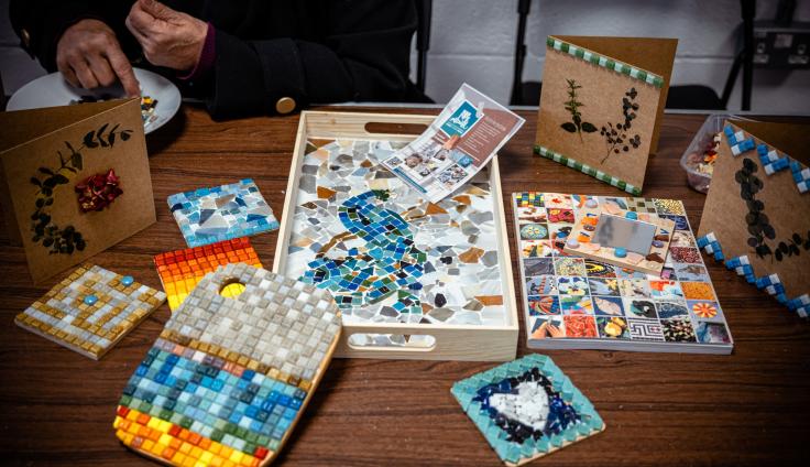 Trays on a table full of small colourful mosaic tiles.