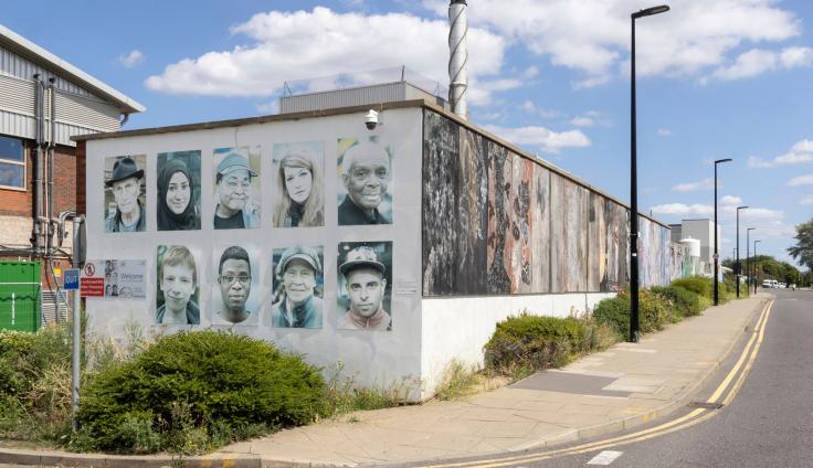 A mural on the side of a building depicting nine portraits of people.