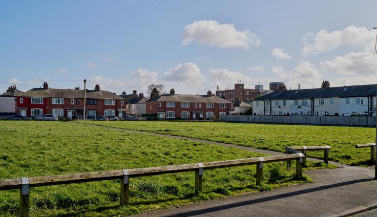 A large grassy recreation area in front of houses.