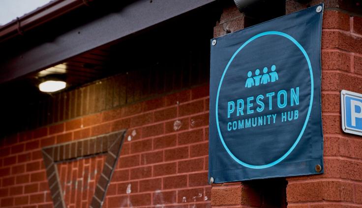 A sign outside a red-brick building, reading 'Preston Community Hub.'
