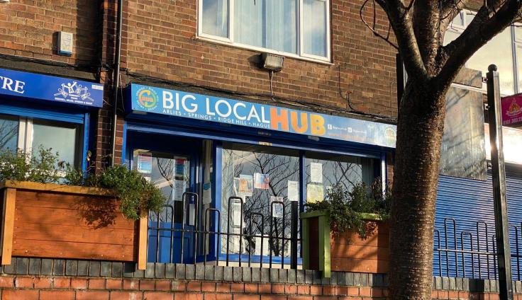 A red-brick building with a shop front below the sign 'Big Local Hub.'