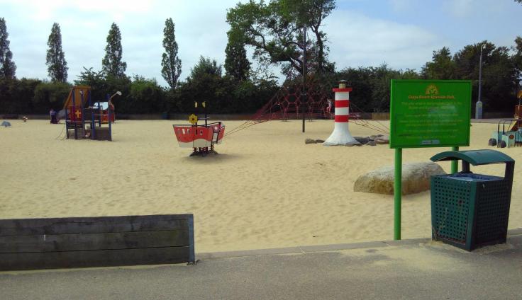 A sandy area in a parkland, with play equipment.