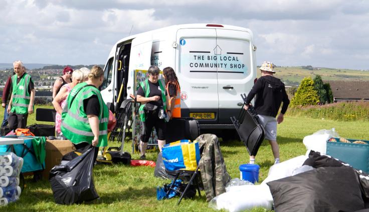 Volunteers busy setting up for an event, with the Big Local Community Shop van in the background.