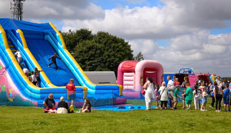 The Shadsworth and Whitebirk Big Local summer carnival, with children playing on an inflatable slide and families gathered around on a field.