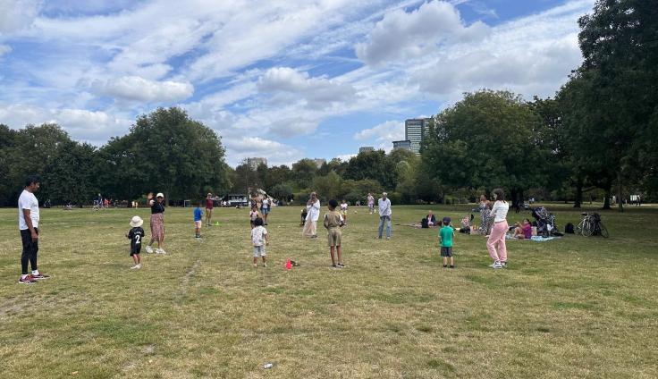 A playing field surrounded by trees, with a group of people playing sports.