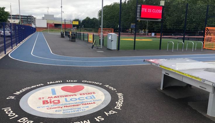 An athletics area with a blue running track and colourful logos painted onto the floor.