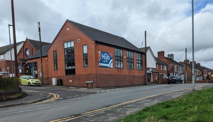 A red-brick building on a junction with large glass windows.