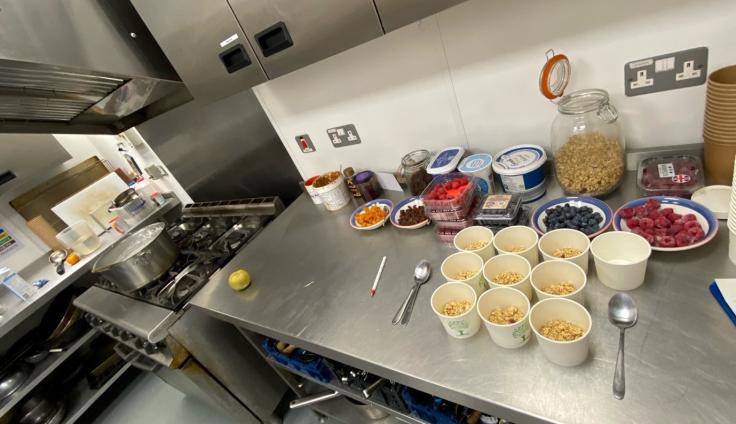 Looking down onto a steel catering kitchen worktop with assorted breakfast items neatly laid out.