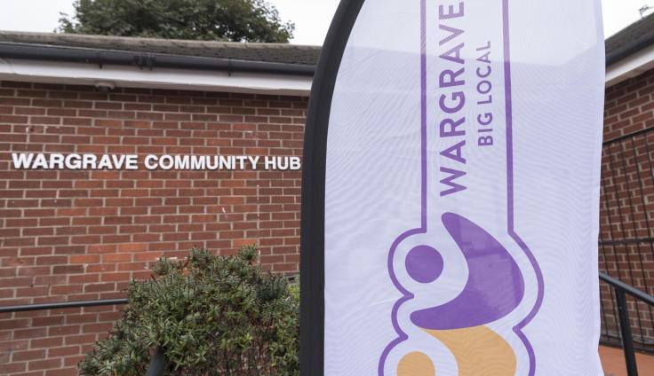 A red-brick building with a white lettered sign reading 'Wargrave Community hub' and a banner in the foreground.