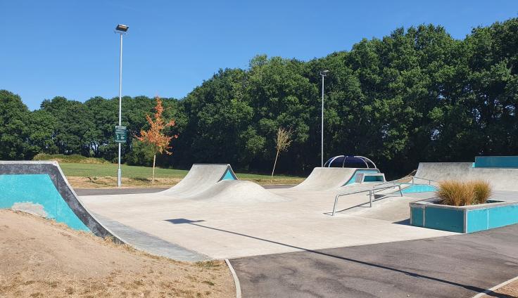 A series of different skate ramps and rails, with trees in the background.