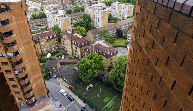 Looking down from a very tall red-brick housing block onto other buildings down below.