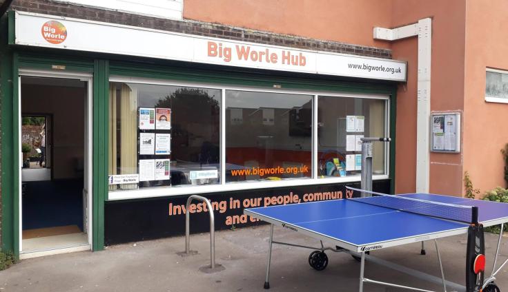 A single-storey shop front below a sign reading 'Big Worle Hub', with a table-tennis table in front of the building.