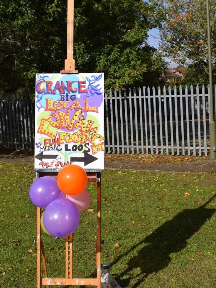 A brightly-coloured poster on a wooden easel, with balloons.