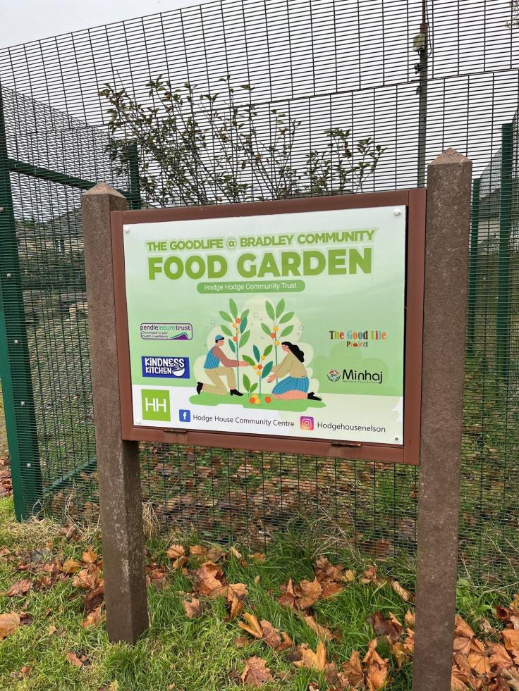 A wood-framed colourful sign that reads 'Food garden' against a steel mesh fence.