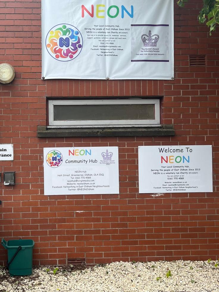 A brick wall with some colourful signs on it, saying 'Welcome to Neon'.