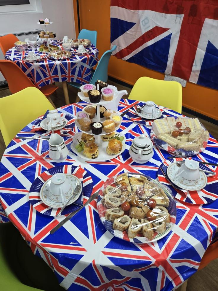 Sandwiches and cupcakes laid out on a tablecloth decorated with the Union Flag, and a large flag in the background.