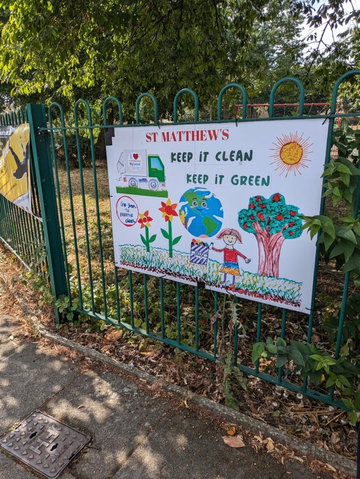 A colourful poster with felt-tip drawings of figures and trees reading 'Keep it clean, keep it green'.