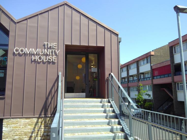 A modern building with wooden-effect cladding and a sign reading 'The Community House'.