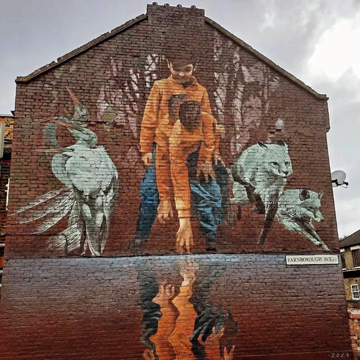 A mural covering the side of a red-brick building depicting a young person bending down towards a reflecting pool.